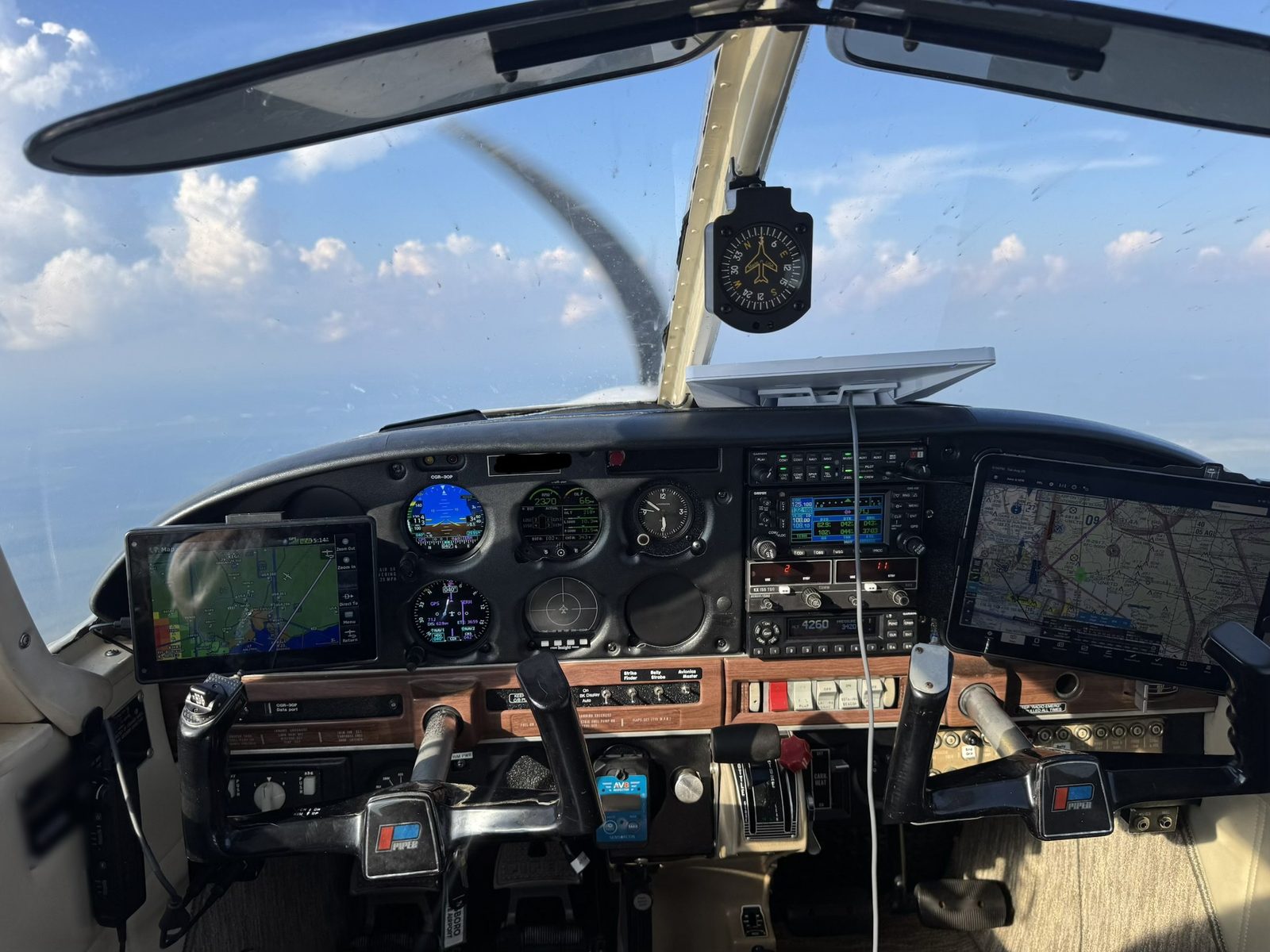 The Warrior II instrument panel in flight over the Emerald Coast, with Garmin G5 displays, a Garmin GNS 430 and a tablet moving map